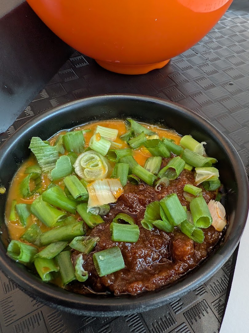 A close-up of a delicious dish featuring two distinct sauces, generously topped with fresh green onions.