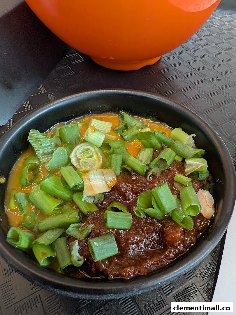 A close-up of a delicious dish featuring two distinct sauces, generously topped with fresh green onions.