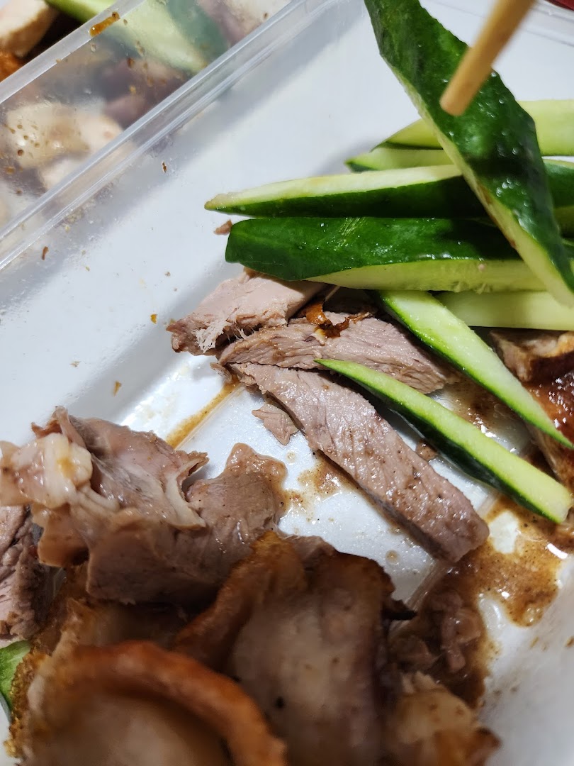 Close-up of sliced duck and fresh cucumber in a takeaway container, ready to eat.