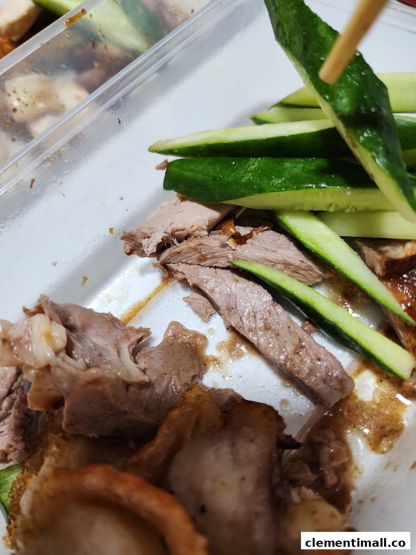 Close-up of sliced duck and fresh cucumber in a takeaway container, ready to eat.