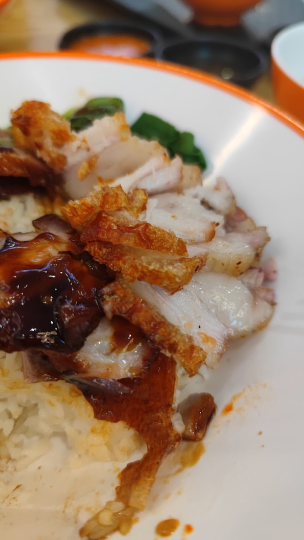 A close-up of a delicious plate featuring crispy roasted pork belly and char siu over rice.