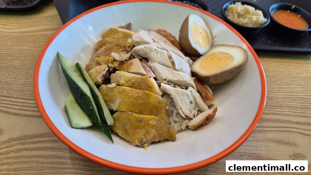 A plate of Hainanese chicken rice with poached and roasted chicken, braised eggs, and cucumber.