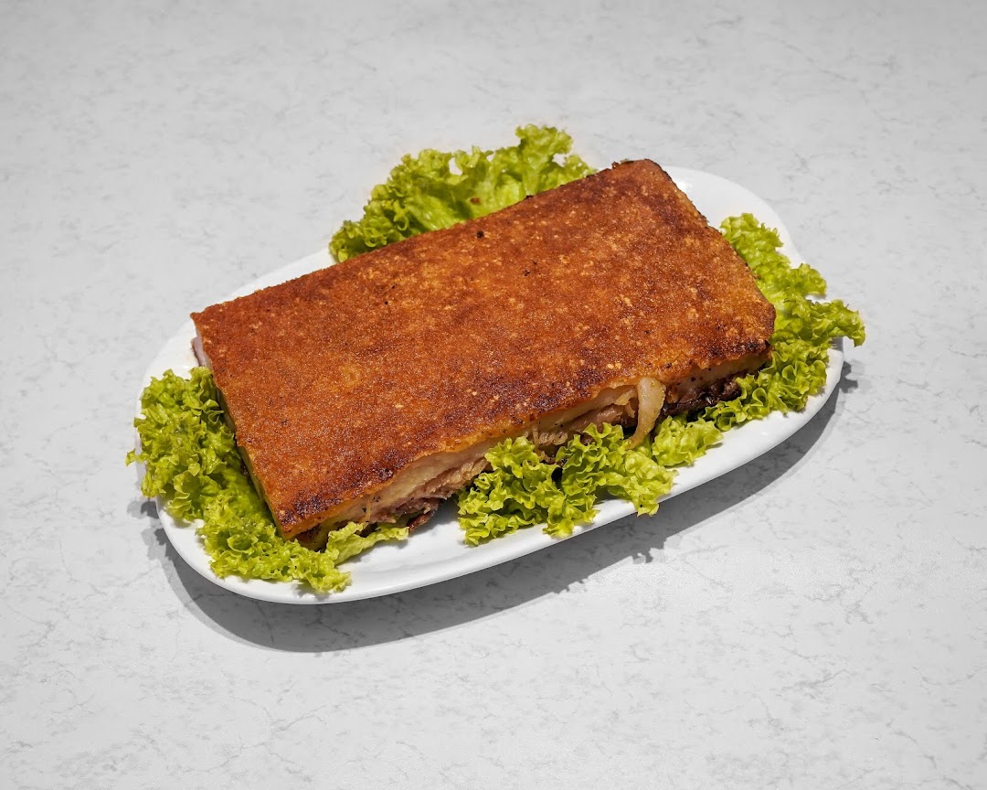 A large, rectangular piece of crispy roasted pork belly served on a bed of fresh green lettuce.