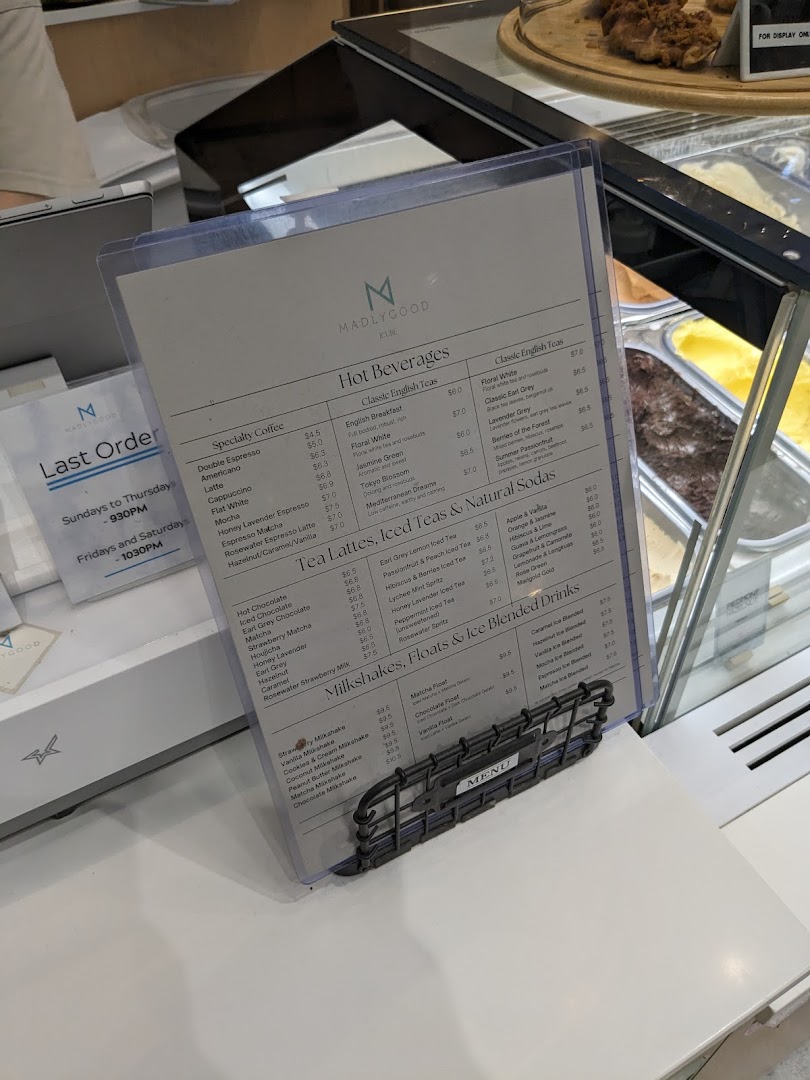 Detailed menu for MADLYGOOD, featuring hot beverages, teas, milkshakes, and floats.