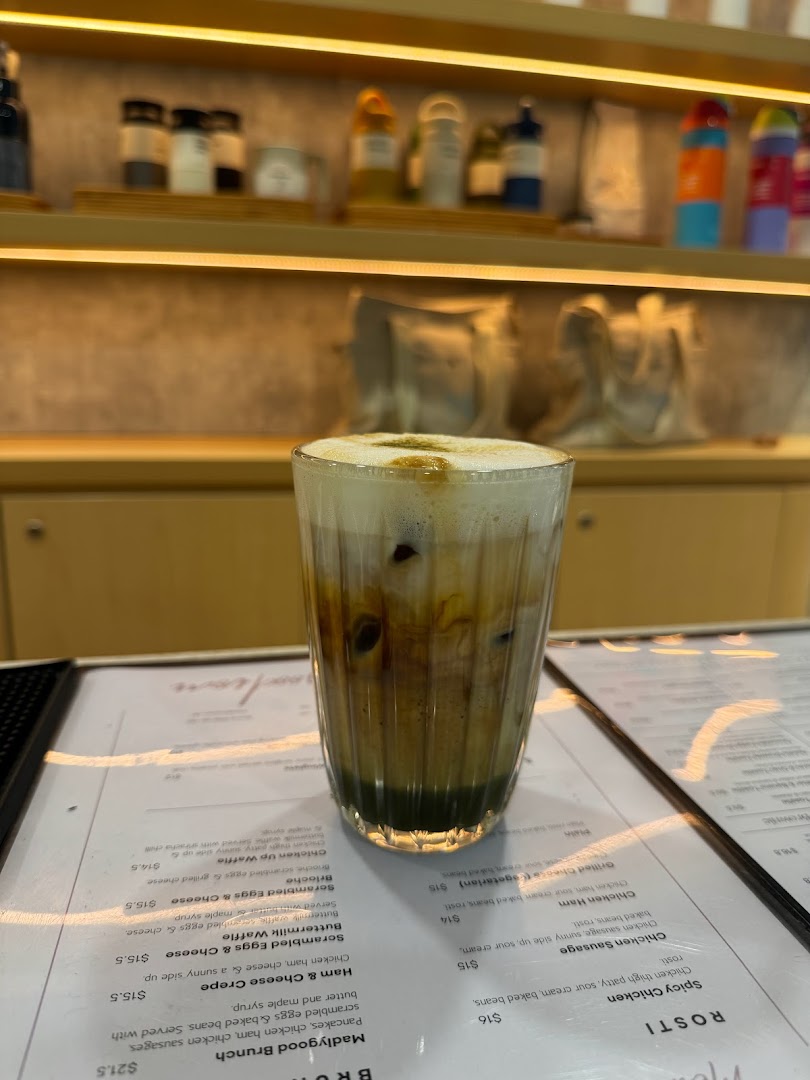 A vibrant layered drink on a table, with a menu partially visible in the foreground.