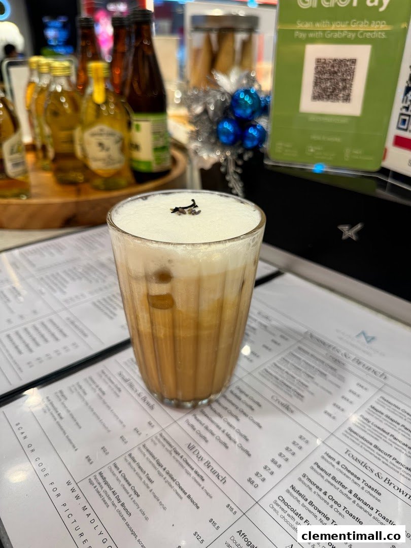 A refreshing iced drink with foam, placed on a detailed menu at MADLYGOOD.