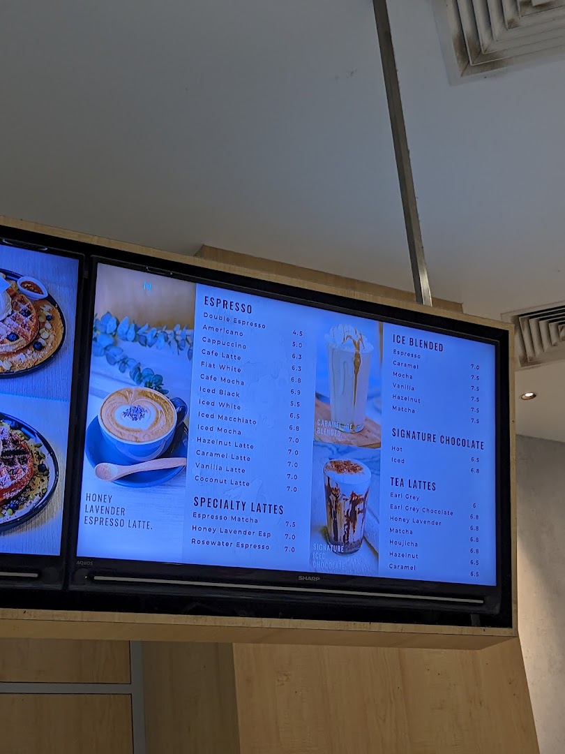 A digital menu board displaying a variety of coffee, blended drinks, and tea lattes.