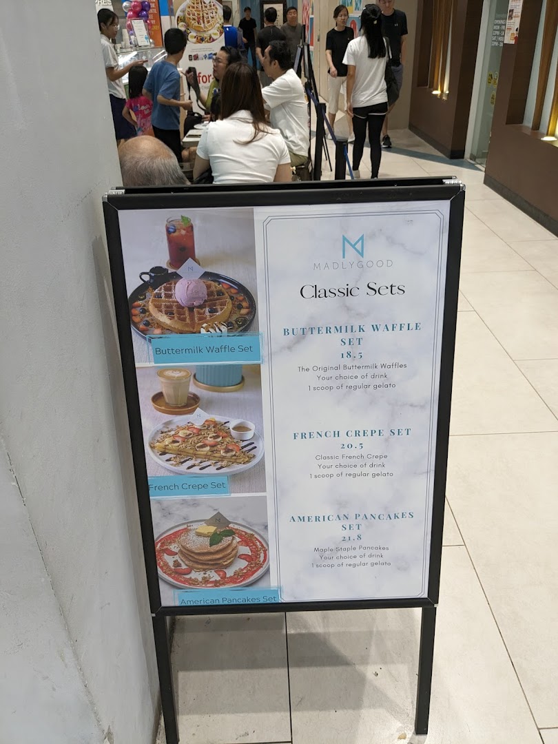A menu board for MADLYGOOD showcasing classic waffle, crepe, and pancake sets with prices.