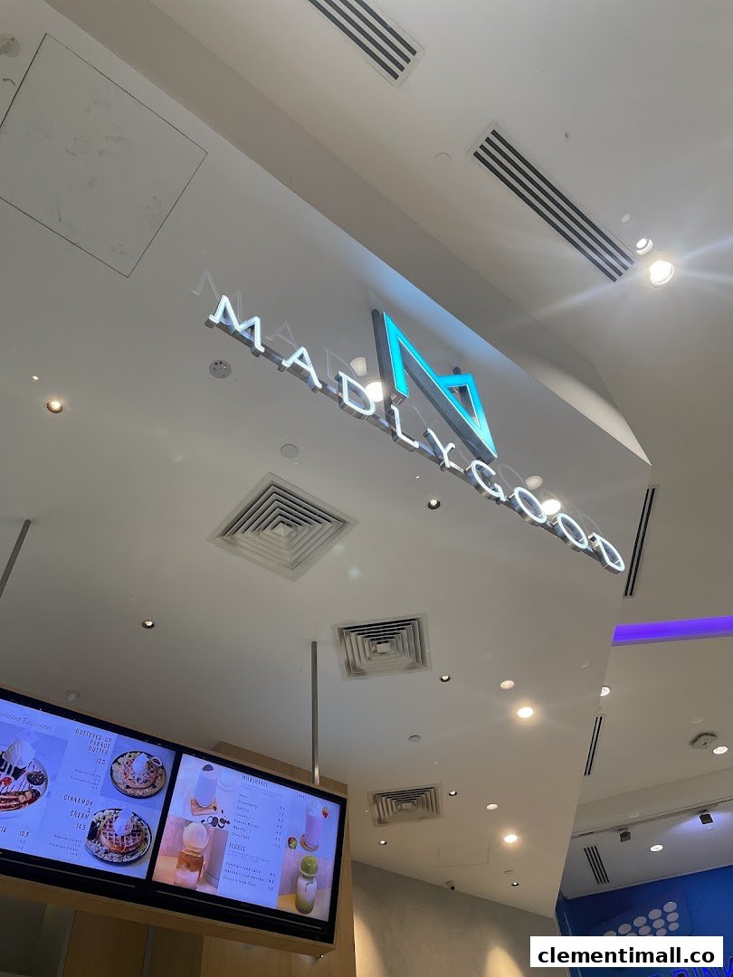 Interior view of MADLYGOOD featuring its illuminated logo and a digital menu board displaying waffles, milkshakes, and floats.
