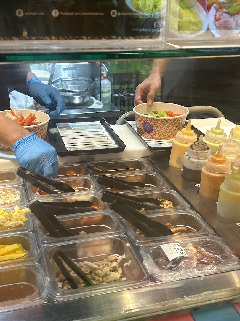 Staff in blue gloves prepare custom sushi/salad bowls with fresh ingredients and sauces at Maki-San.