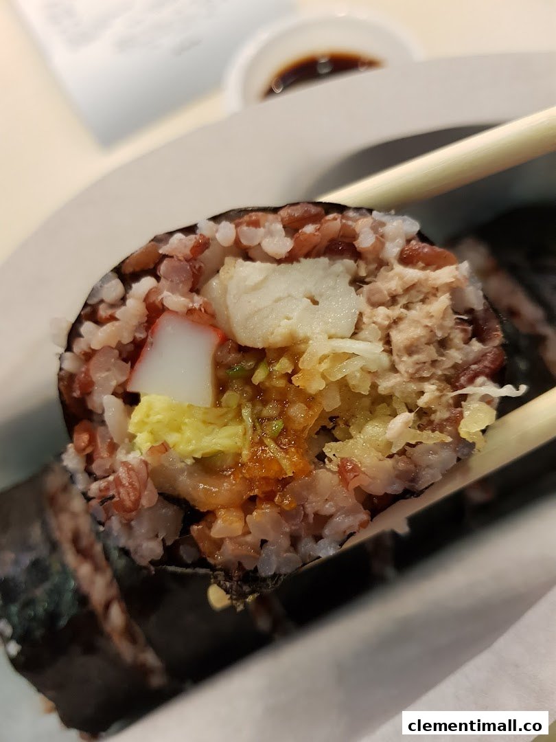 Close-up of a colorful sushi roll with various fillings, held by chopsticks.