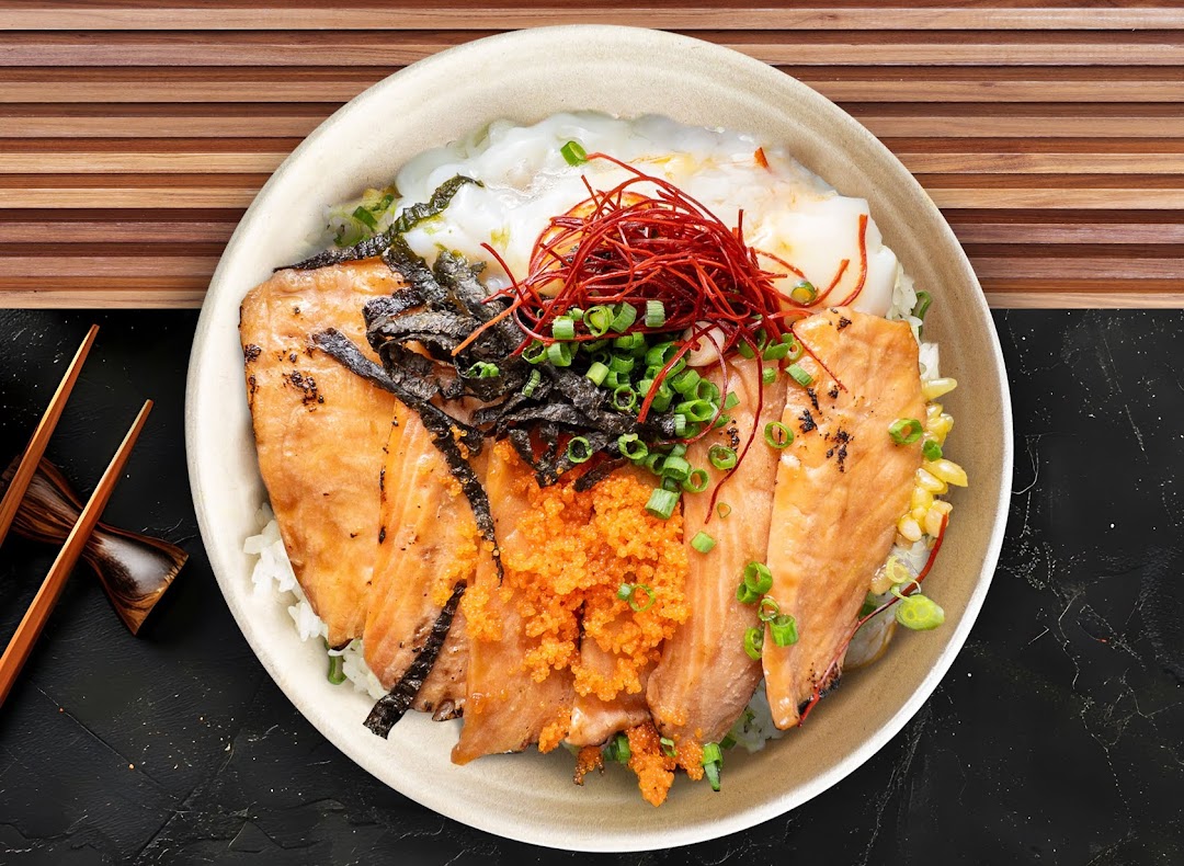 A vibrant bowl of grilled salmon, roe, seaweed, and spring onions over rice, with chopsticks.