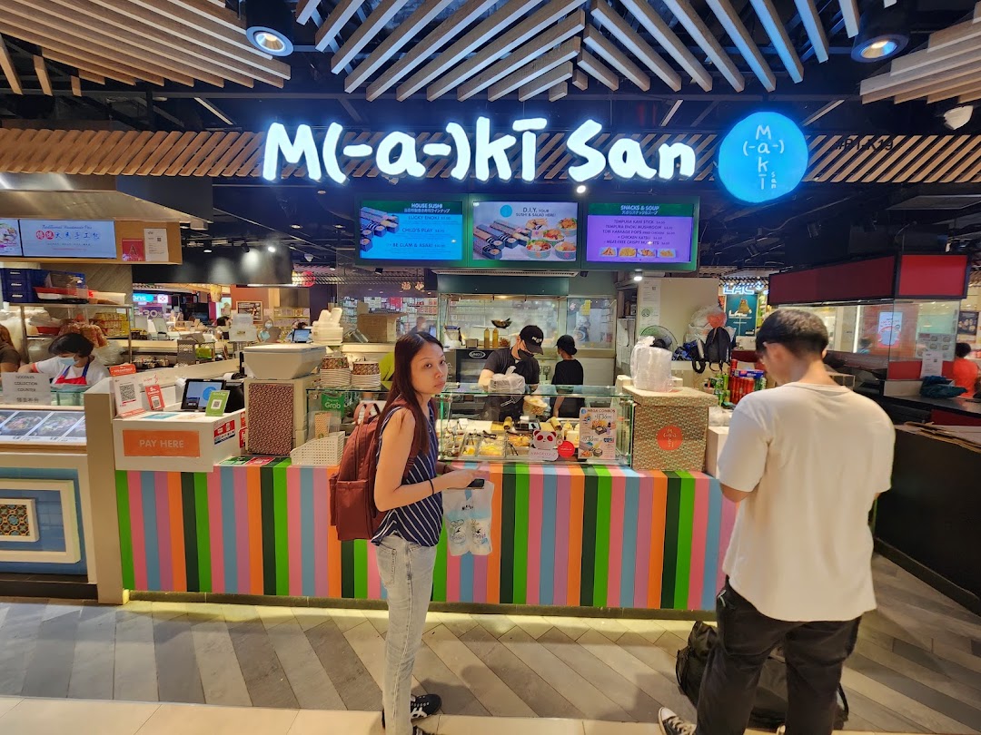 Maki-San's vibrant counter with customers and staff, showcasing their colorful branding and menu screens.