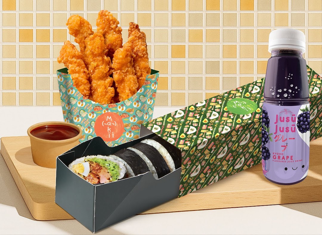 A Maki-San sushi roll, fried chicken, and a grape drink are displayed on a wooden board.