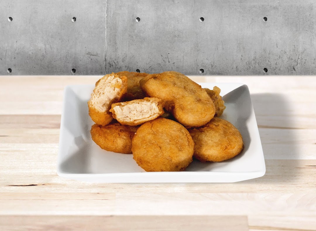 A white plate filled with golden-brown fried nuggets, one broken open to show the tender interior.