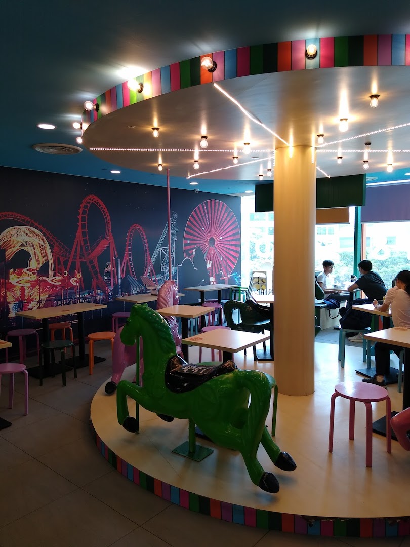 Vibrant interior of Maki-San with a carousel-themed platform, colorful stools, and an amusement park mural.