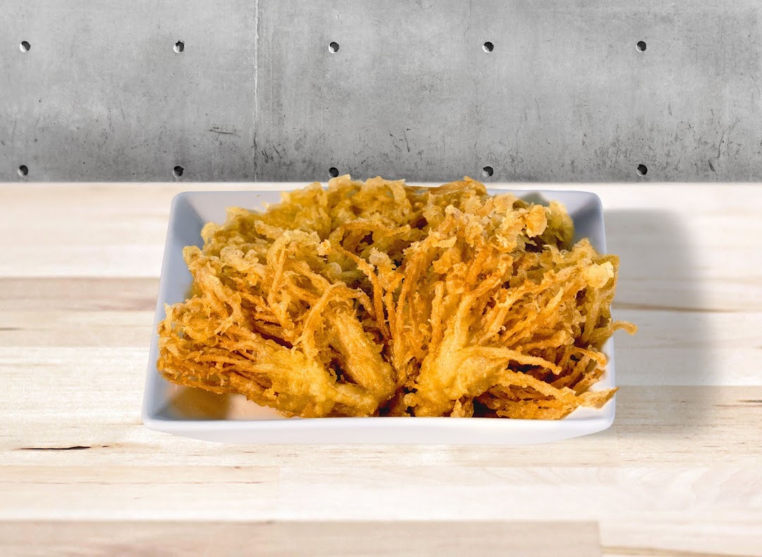 A plate of crispy golden-brown tempura-style enoki mushrooms on a white dish.