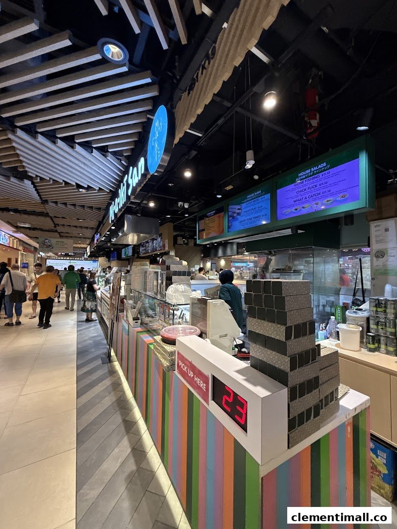 Maki-San's vibrant counter with digital menus, showcasing fresh sushi and salad options in a bustling mall setting.