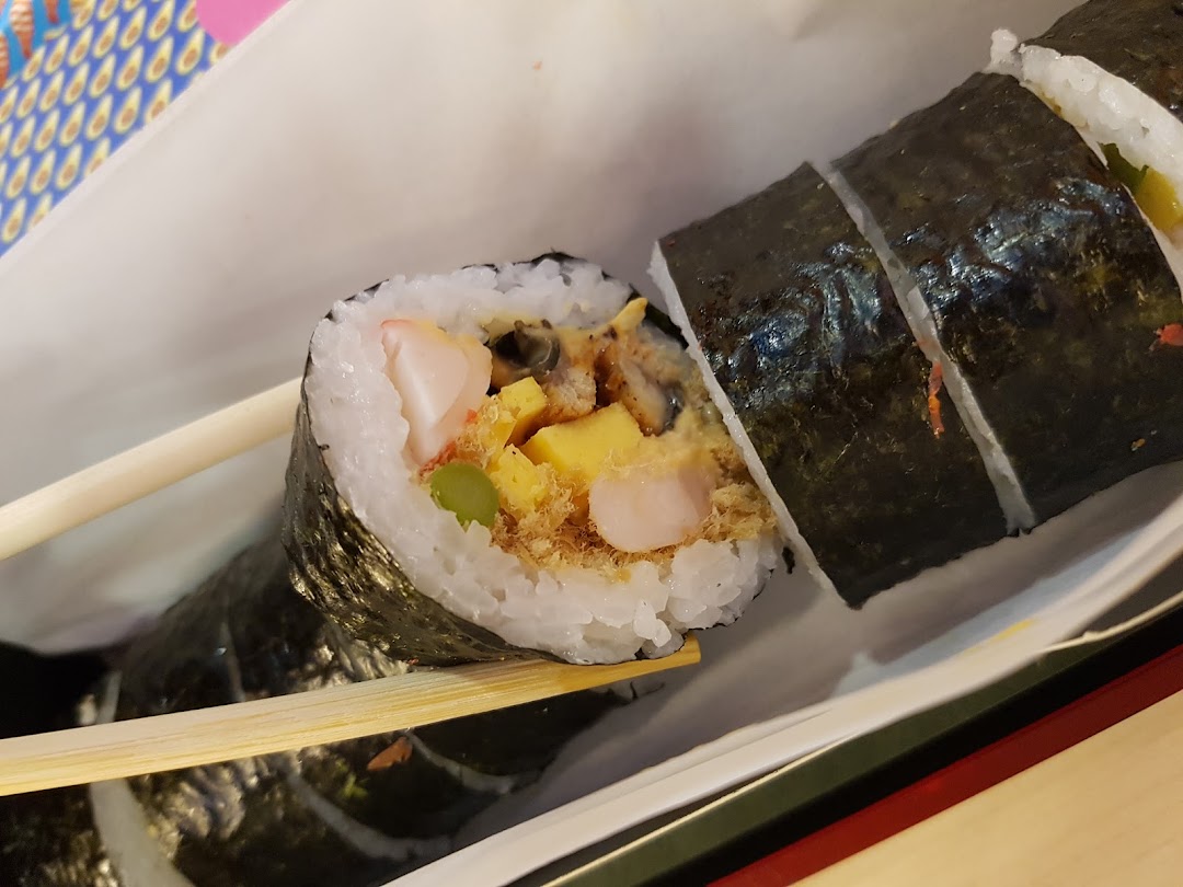 Close-up of freshly prepared sushi rolls with various fillings, held by chopsticks.