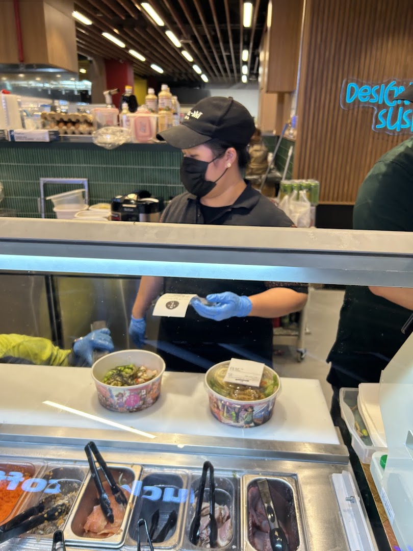 Staff prepares fresh sushi/poke bowls at Maki-San counter, showcasing ingredients and custom orders.
