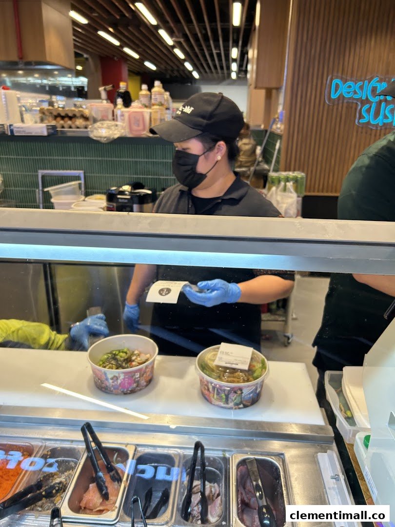 Staff prepares fresh sushi/poke bowls at Maki-San counter, showcasing ingredients and custom orders.