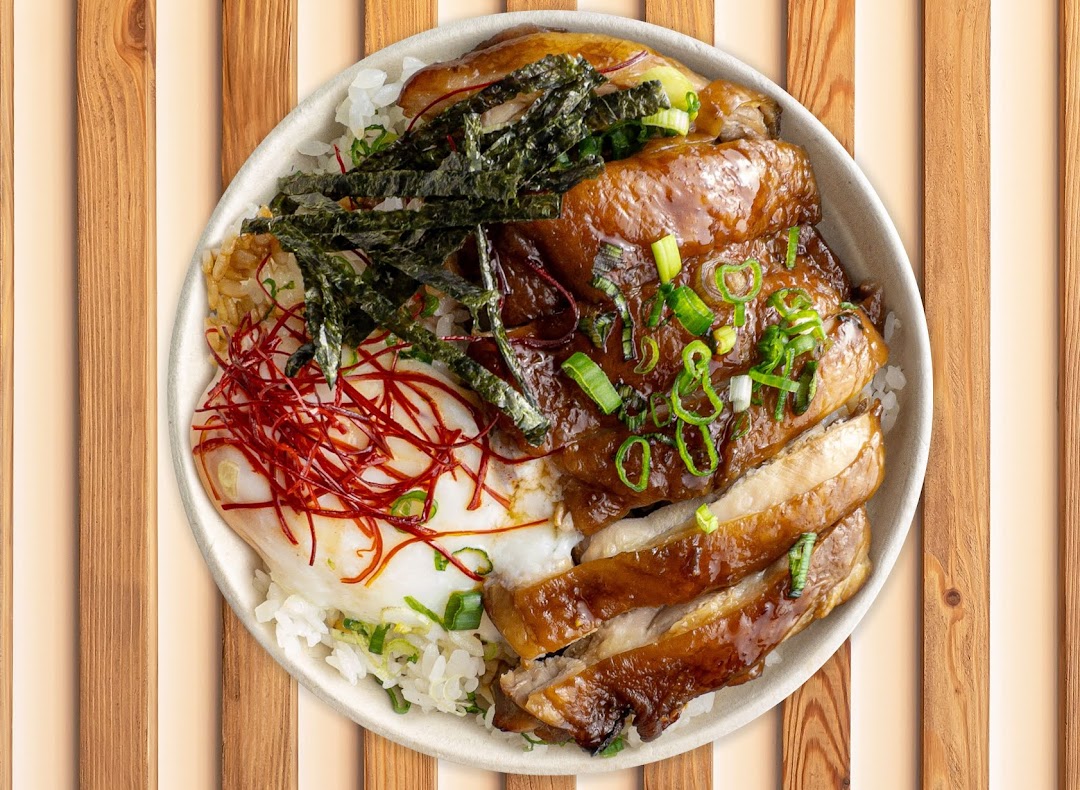 A delicious rice bowl featuring glazed chicken, a fried egg, seaweed, and spring onions.