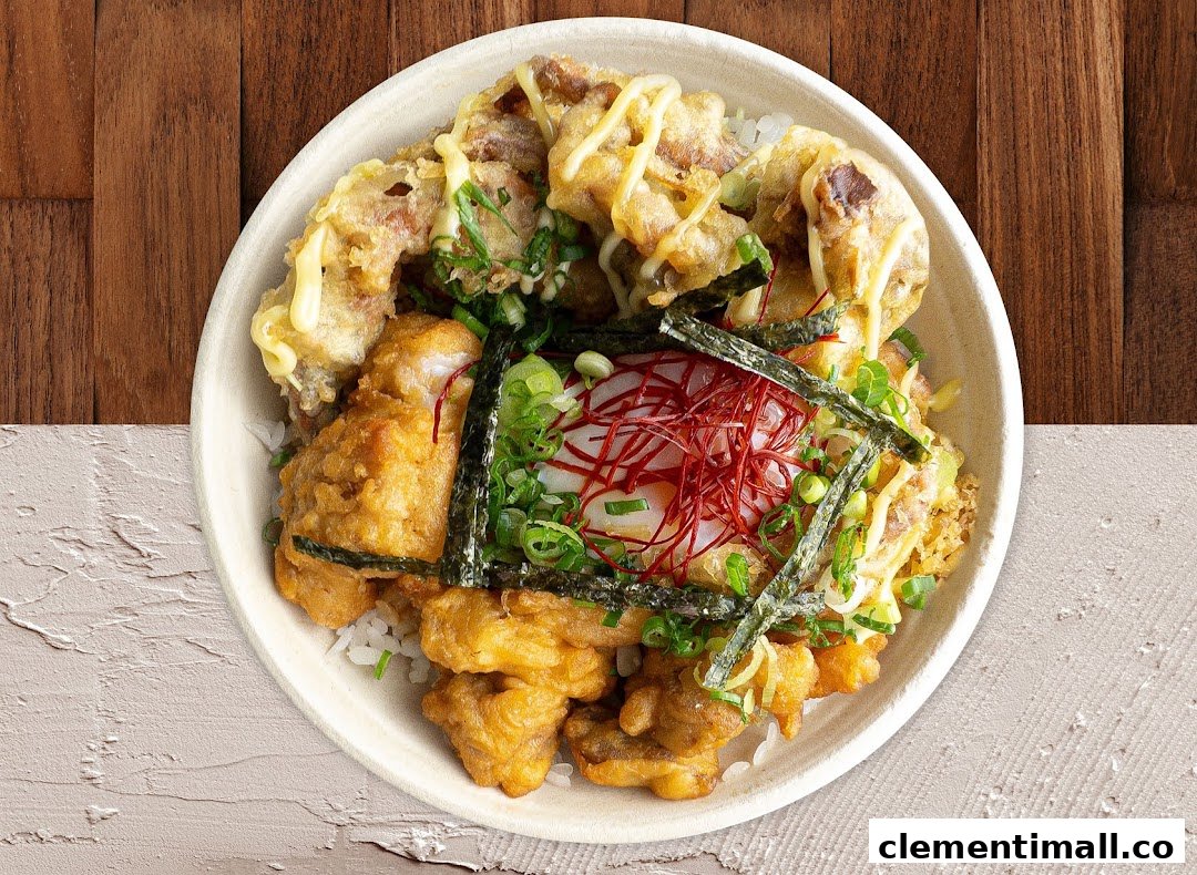 A close-up of a delicious Japanese rice bowl with fried chicken, tempura, egg, and fresh garnishes.