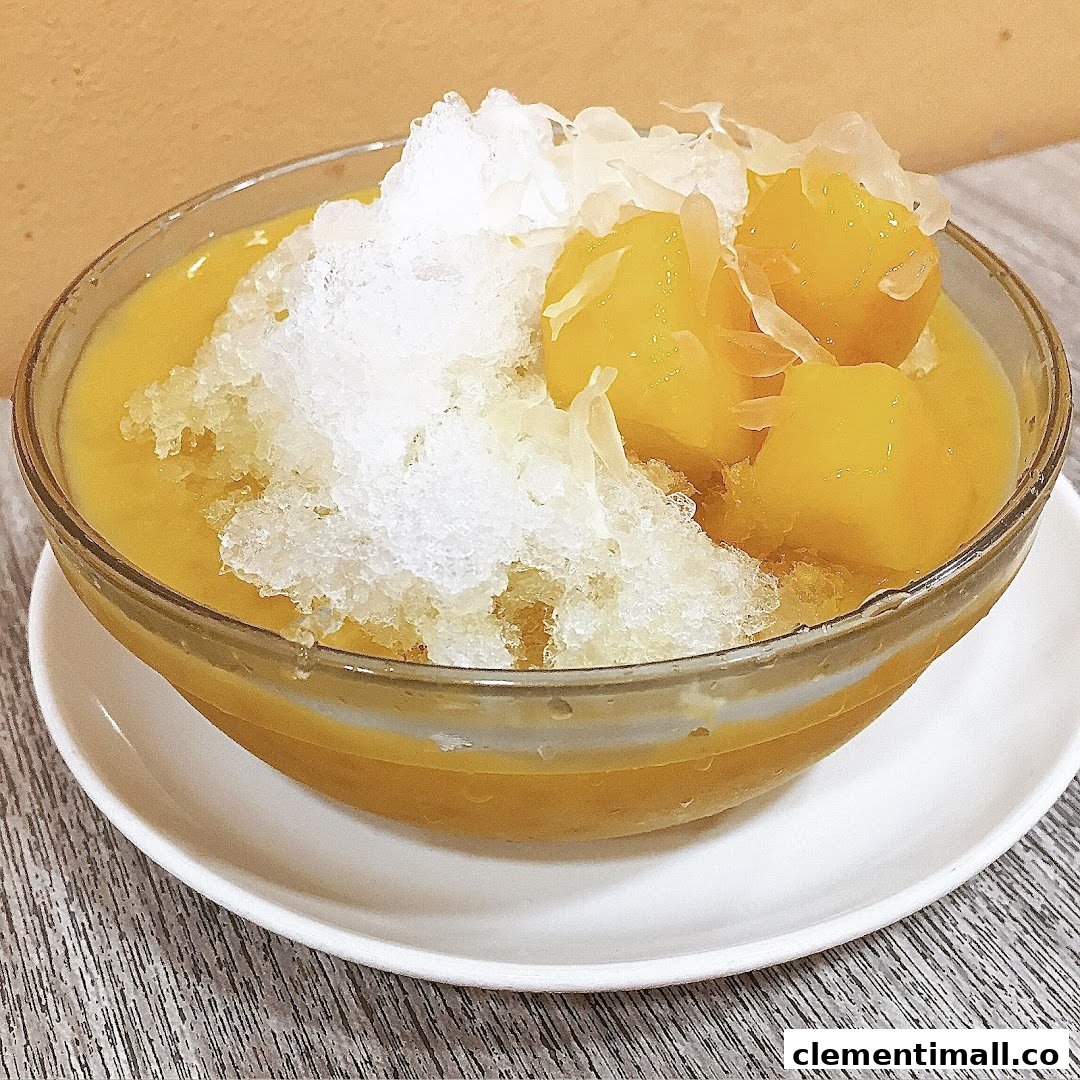 A vibrant bowl of mango dessert with shaved ice and fruit pieces.