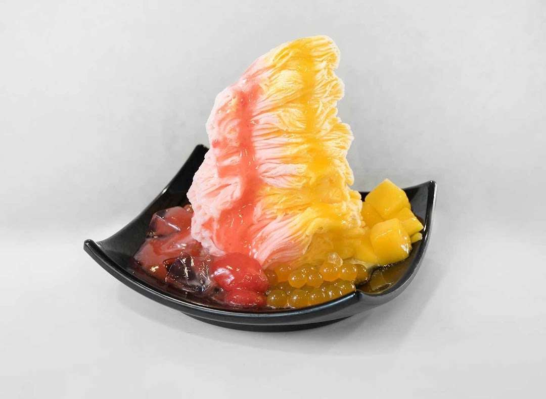 A vibrant shaved ice dessert with fruit, jelly, and popping boba in a black bowl.