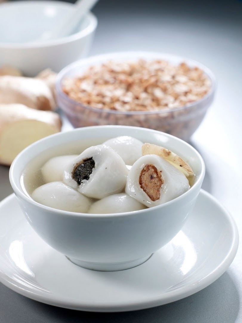 A bowl of traditional glutinous rice balls (tangyuan) with various fillings in ginger soup.