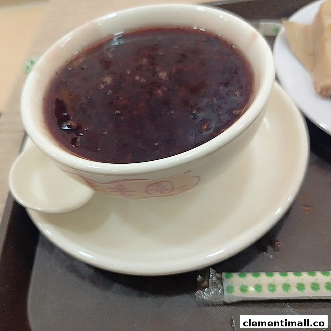 A close-up of a bowl of traditional black sesame dessert served on a tray.