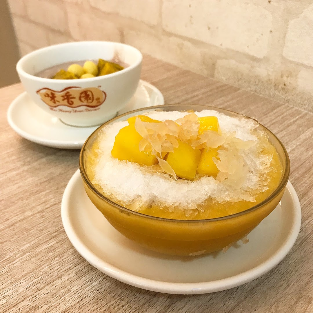 Two bowls of traditional Chinese desserts, including mango shaved ice and a taro-based soup.