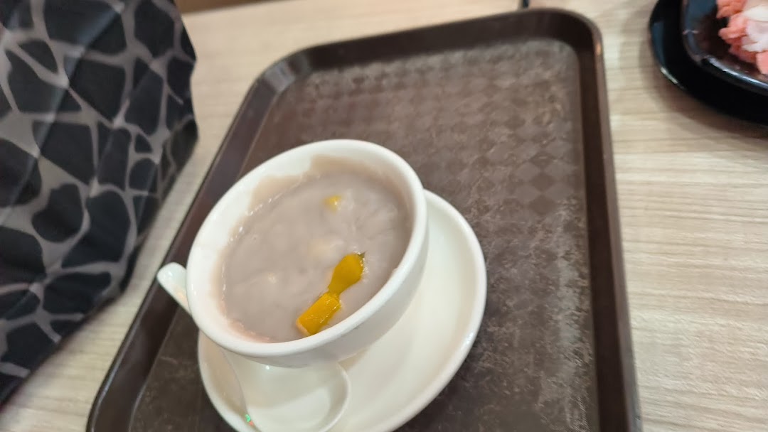 A close-up of a bowl of purple taro dessert with mango pieces on a serving tray.
