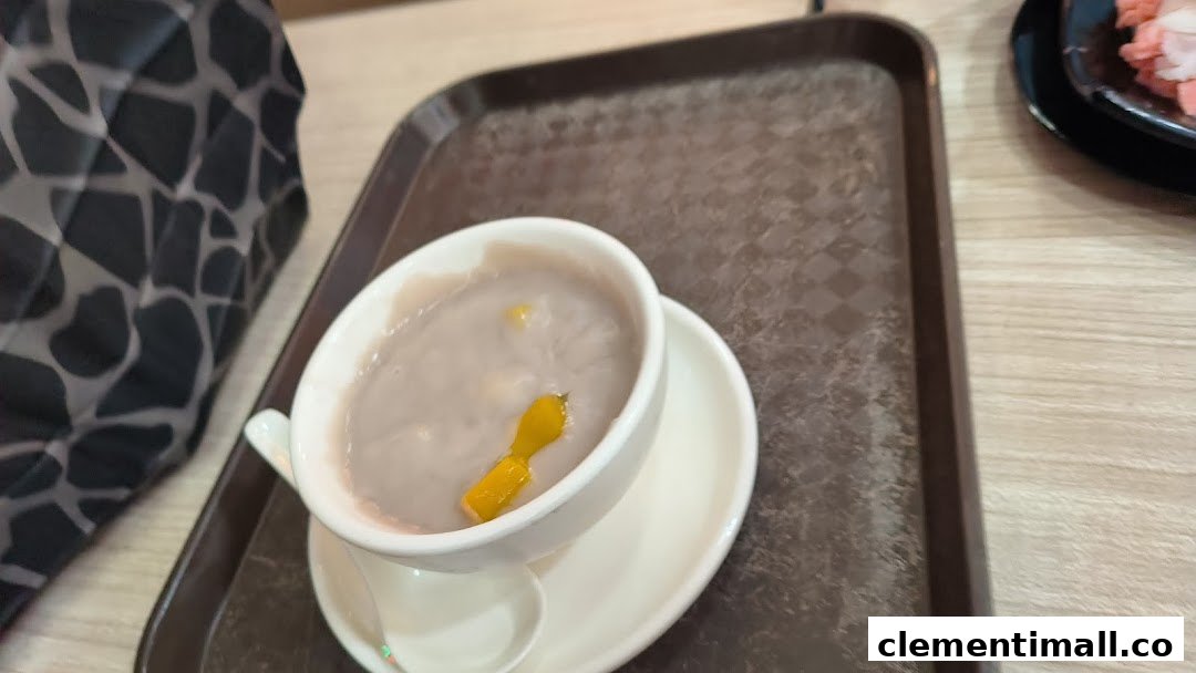 A close-up of a bowl of purple taro dessert with mango pieces on a serving tray.