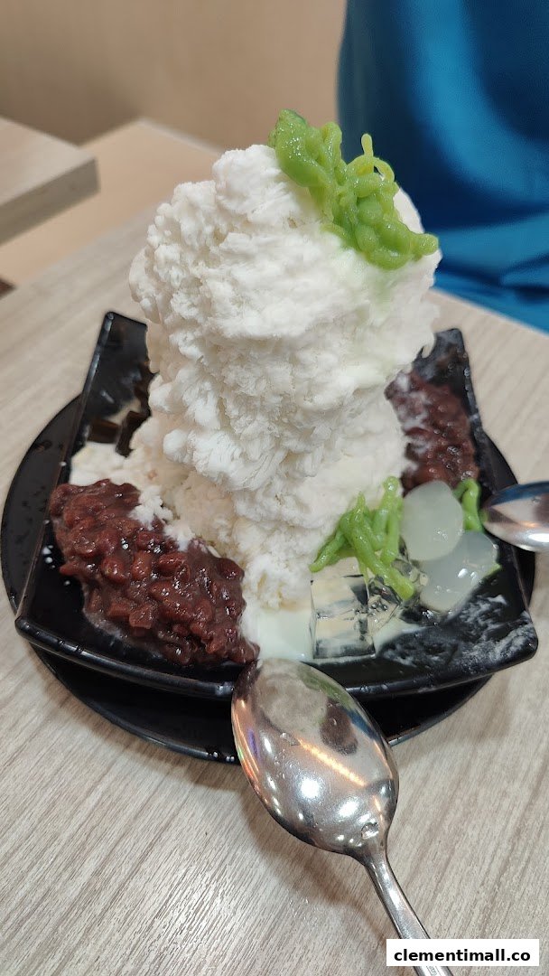 A close-up of a large bowl of refreshing shaved ice dessert with red beans, green cendol, and jellies.