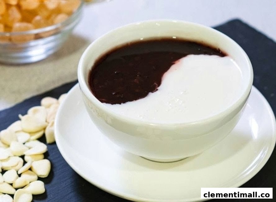 A bowl of traditional Chinese dessert, likely black sesame or red bean paste, with a swirl of white cream.