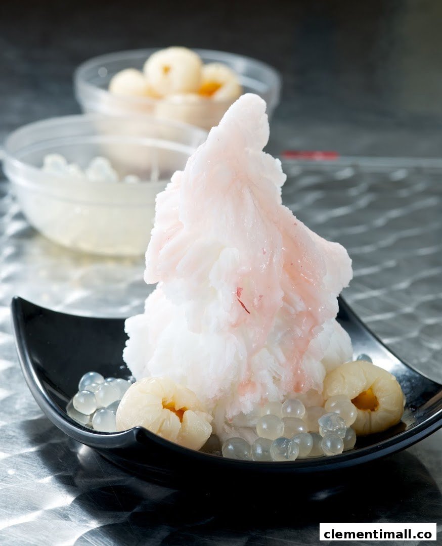 A refreshing shaved ice dessert with lychees and clear tapioca pearls in a black bowl.