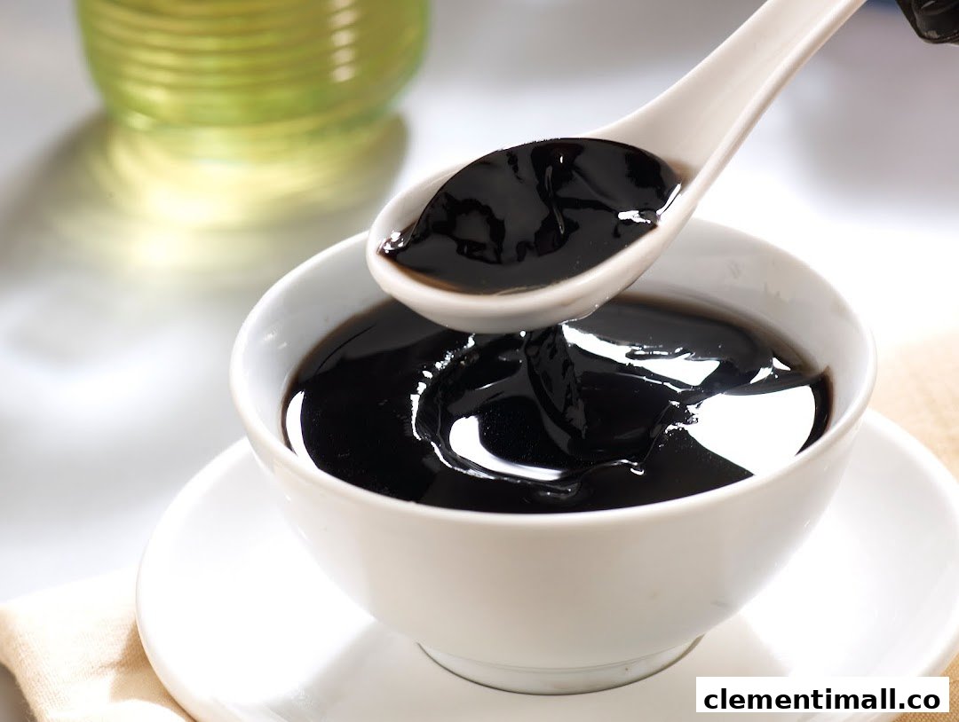 A close-up of a bowl of traditional black herbal jelly dessert being served with a spoon.