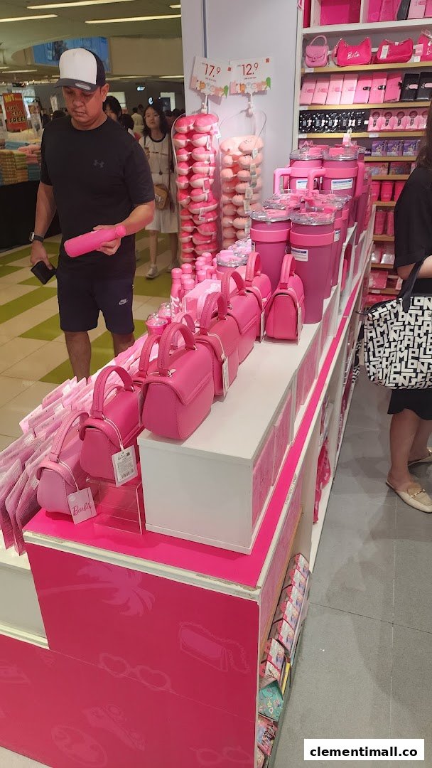 A vibrant display of pink Barbie-themed products, including bags and bottles, inside a MINISO store.