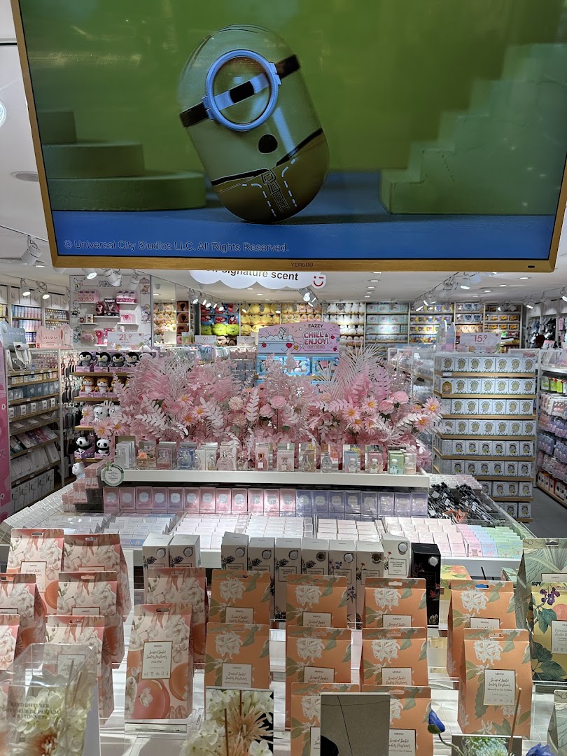 Vibrant interior of MINISO, showcasing diverse lifestyle products, a large screen, and a decorative pink floral display.