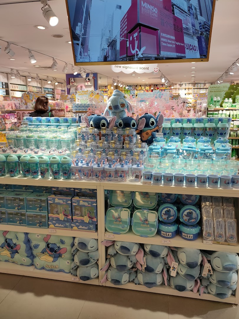 A vibrant display of Stitch-themed merchandise, including plush toys and drinkware, inside a MINISO store.