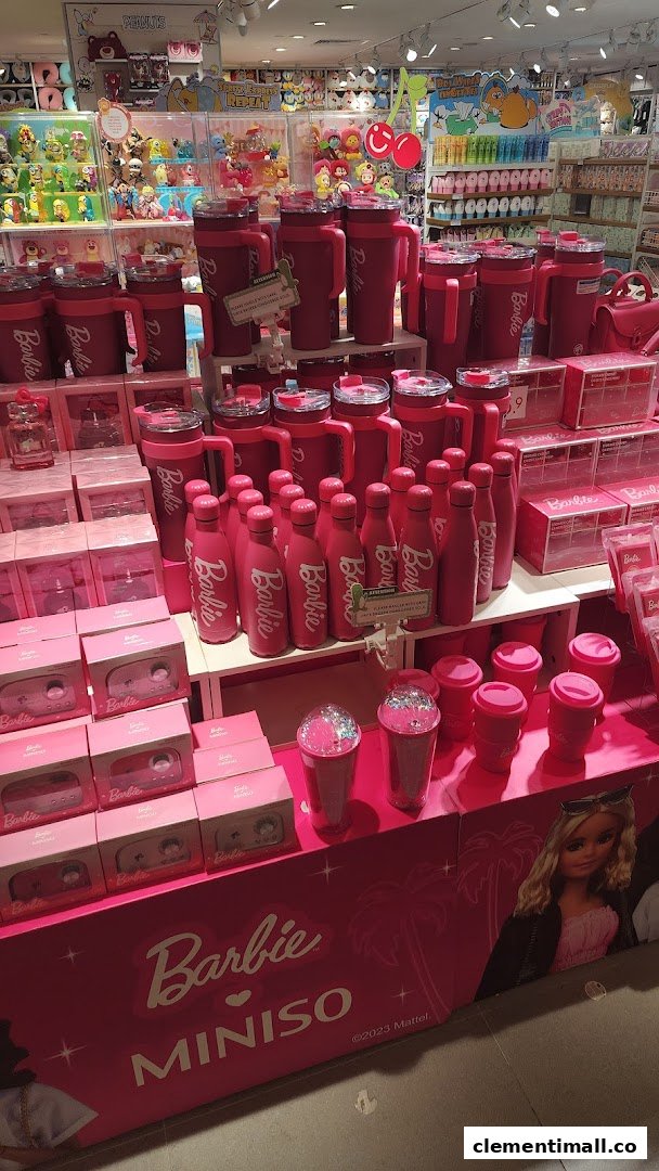 A vibrant display of pink Barbie x MINISO collaboration products, including bottles and tumblers, inside the store.