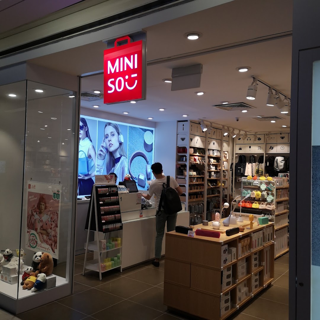 The MINISO shop entrance features a bright red sign and a view of its diverse product displays.