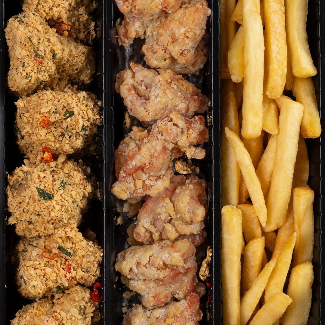 Close-up of a food container featuring crispy fried chicken pieces, some with a spiced coating, and golden french fries.