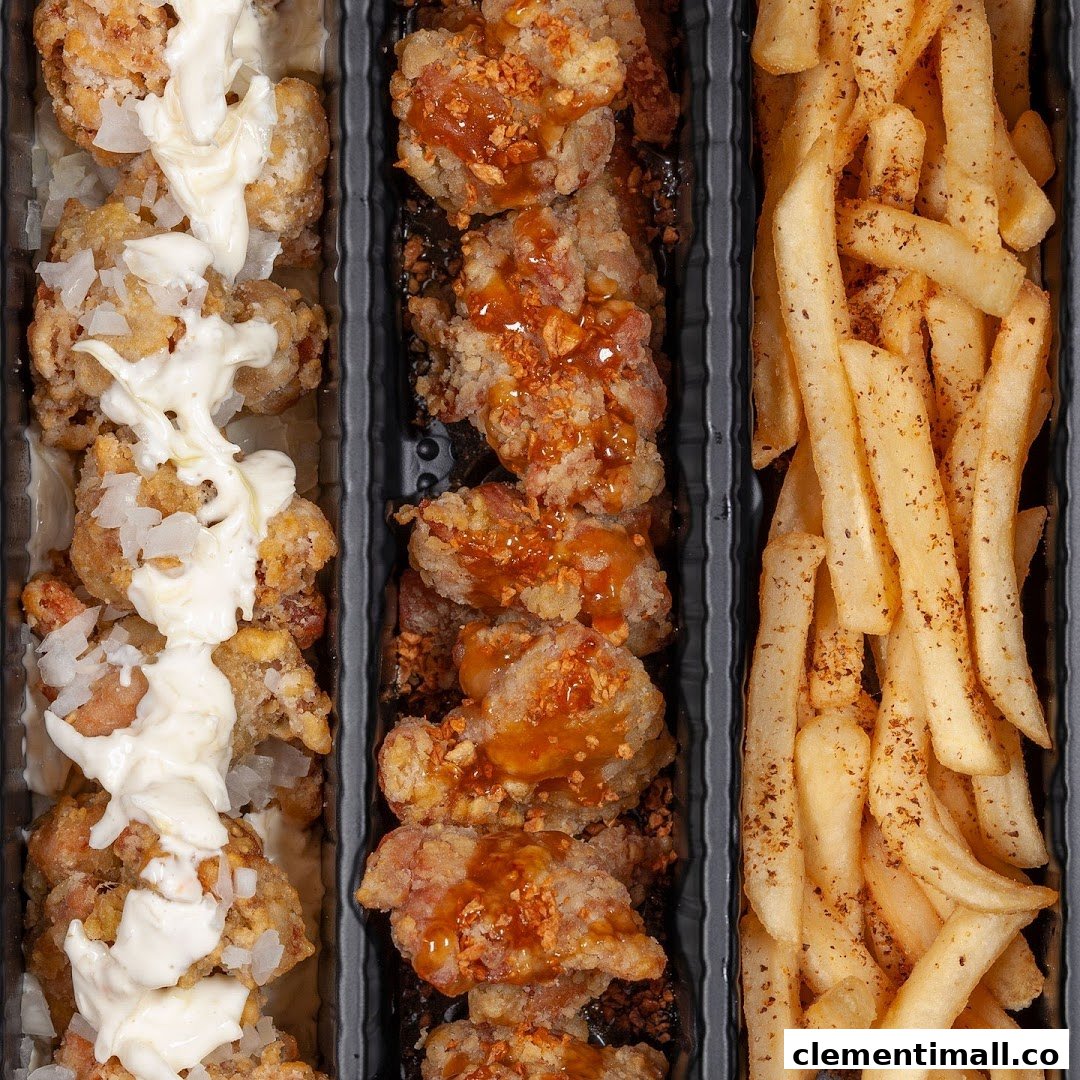 Close-up of fried chicken pieces with various toppings and a side of seasoned fries in a tray.