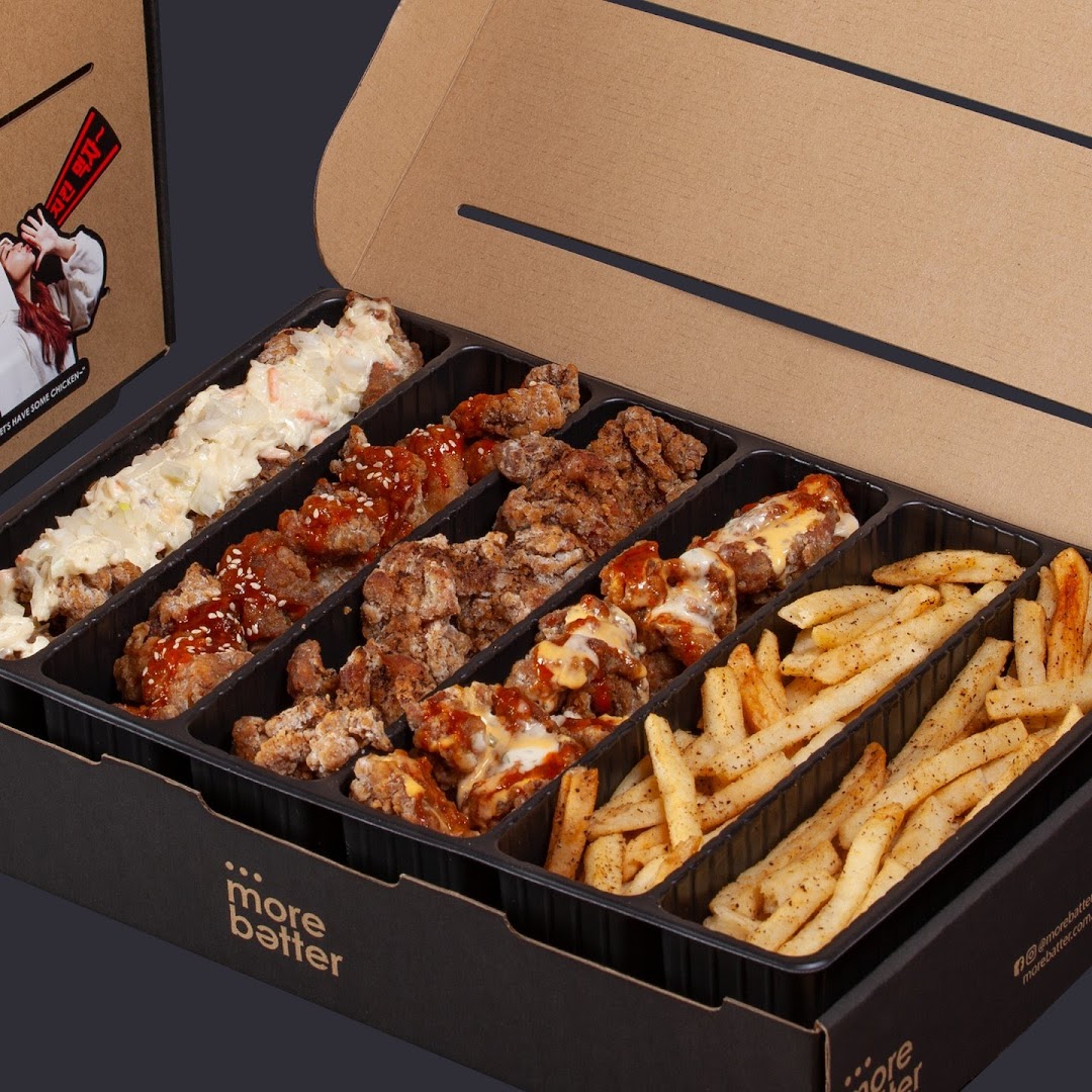 A large box of assorted fried chicken pieces with various sauces and seasoned fries from More Batter.