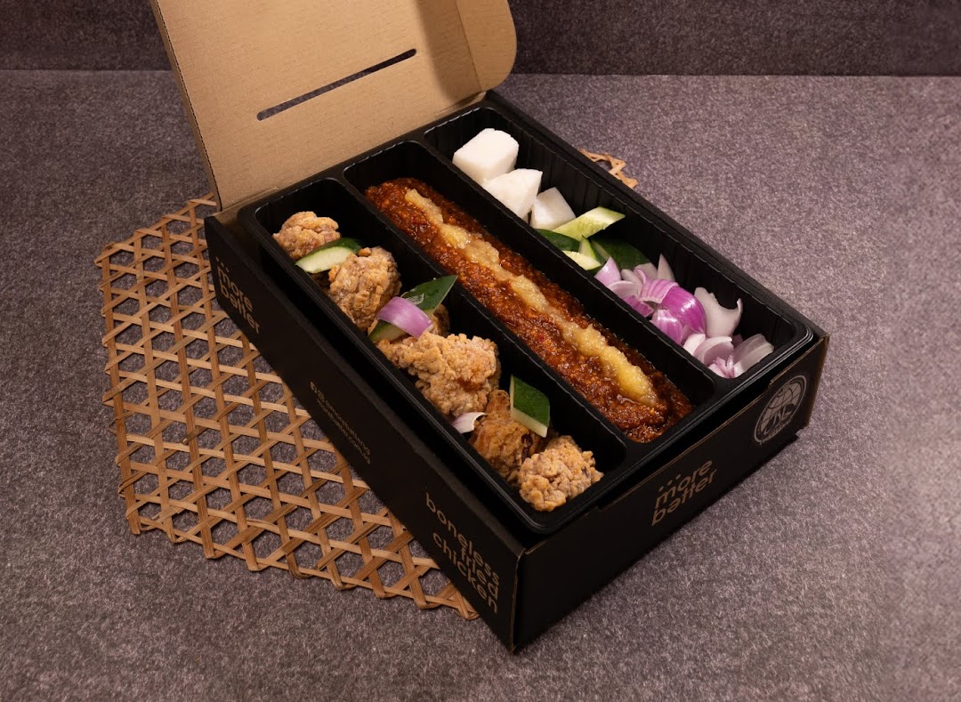 A takeaway box from More Batter featuring boneless fried chicken, sambal, and fresh vegetables.