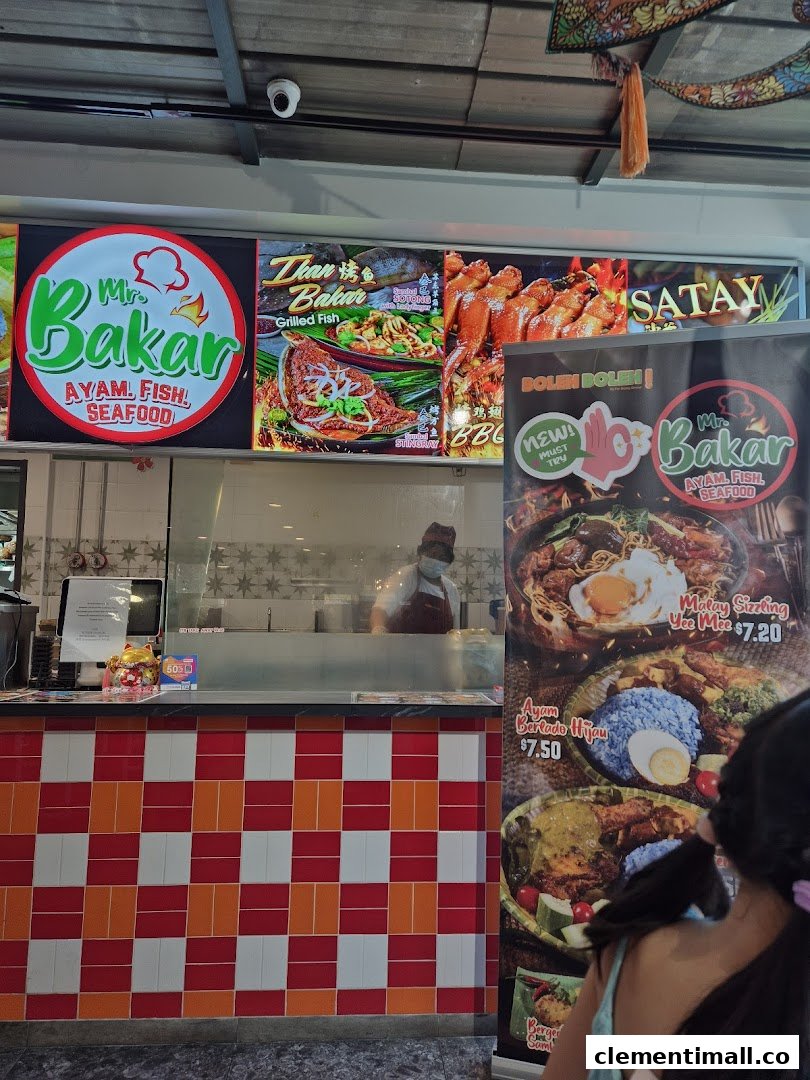 A vibrant food stall counter at Mr Bakar, showcasing grilled dishes and specific menu items with prices.