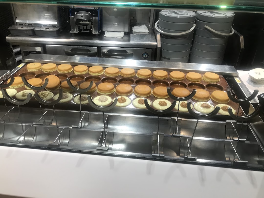 A griddle displays numerous freshly made Mr Bean pancakes, some being filled with various sweet fillings.