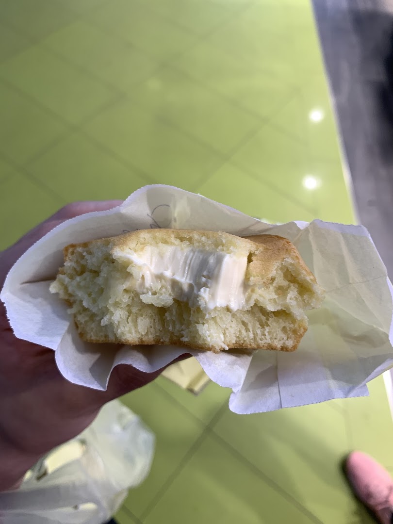 A fluffy pancake filled with creamy white filling, held in a paper wrapper.